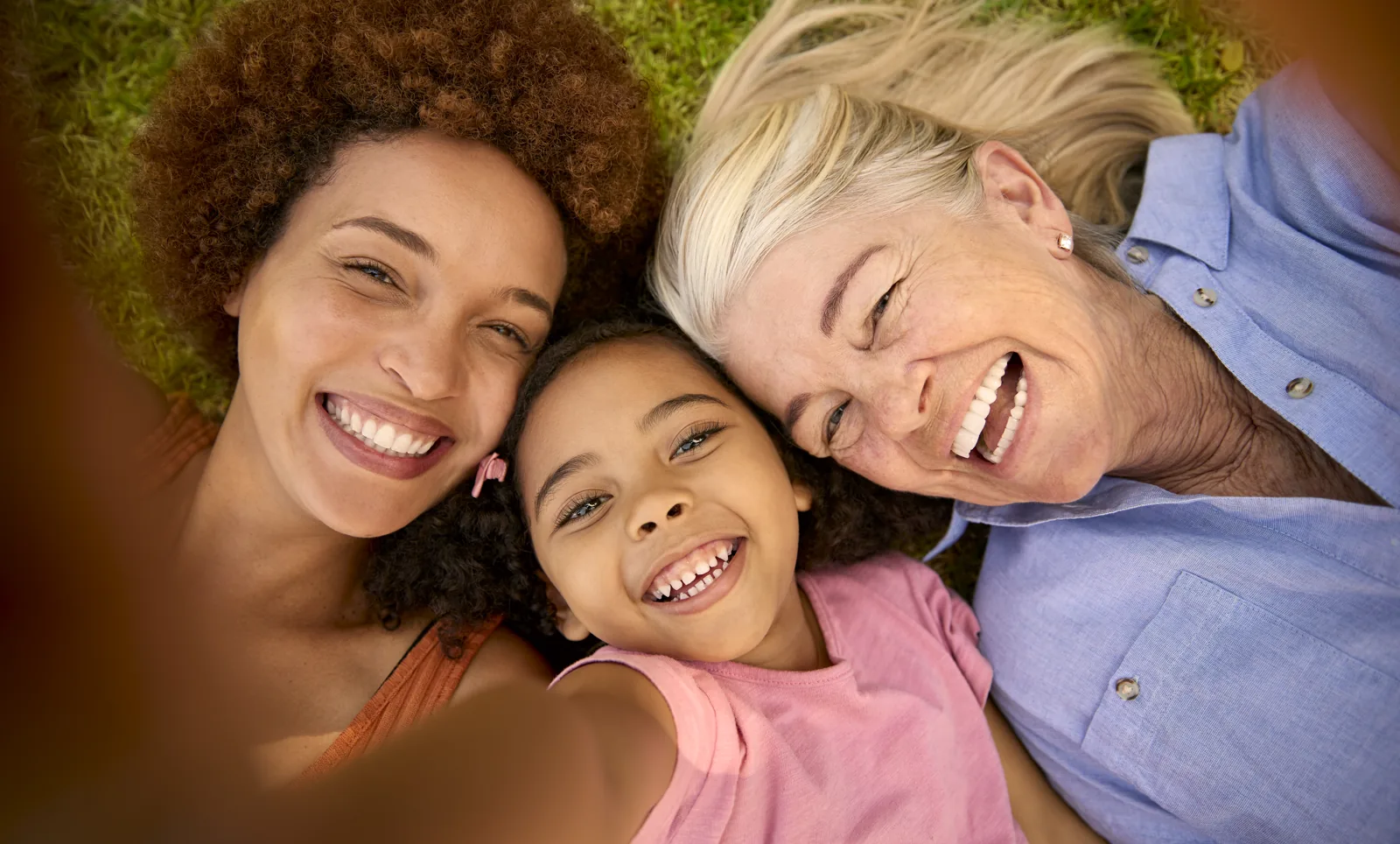 Trois générations d'une famille souriante, allongées dans l'herbe